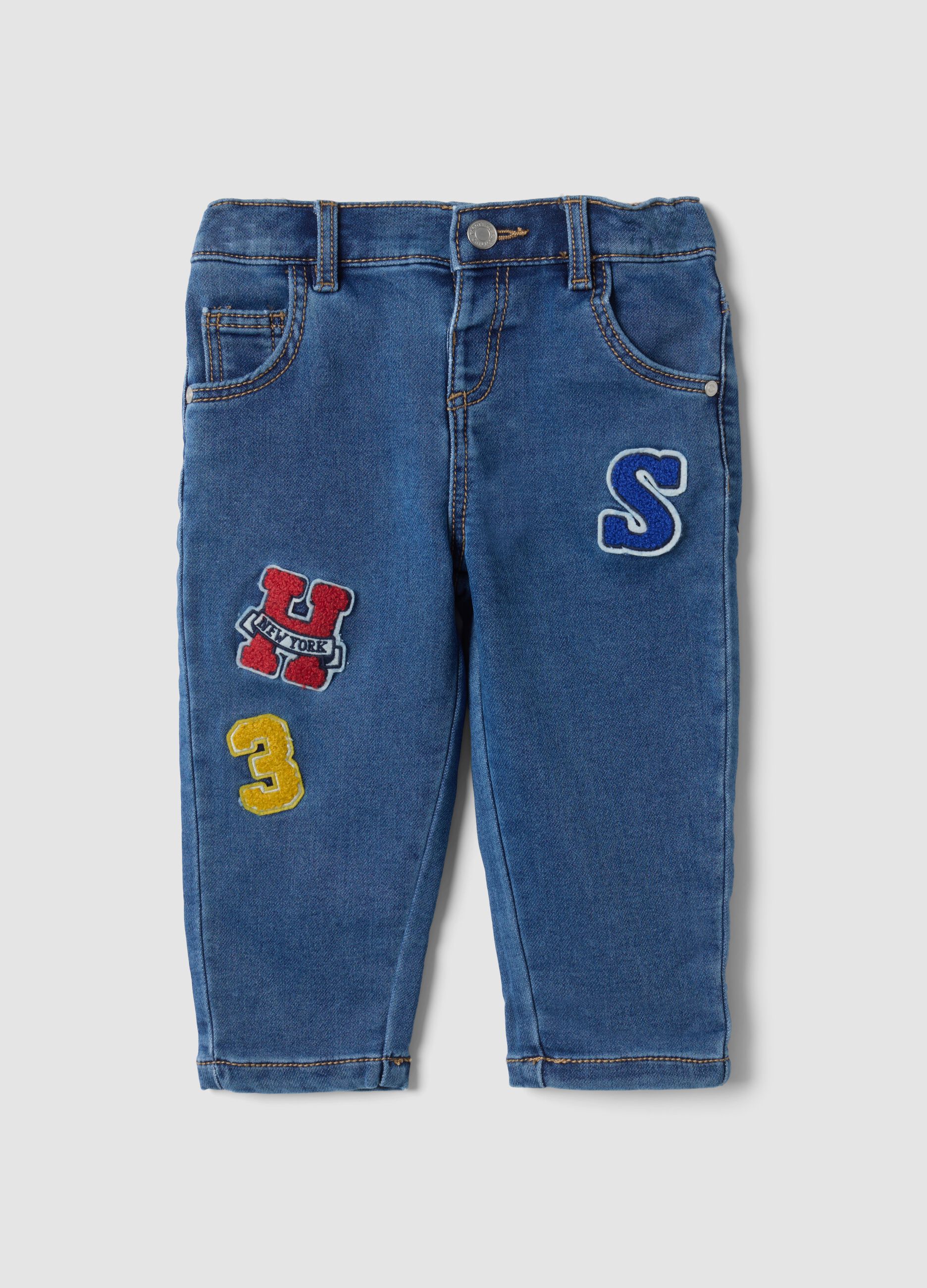 Blue stretch cotton jeans with varsity-style appliqu&eacute;s for baby boy