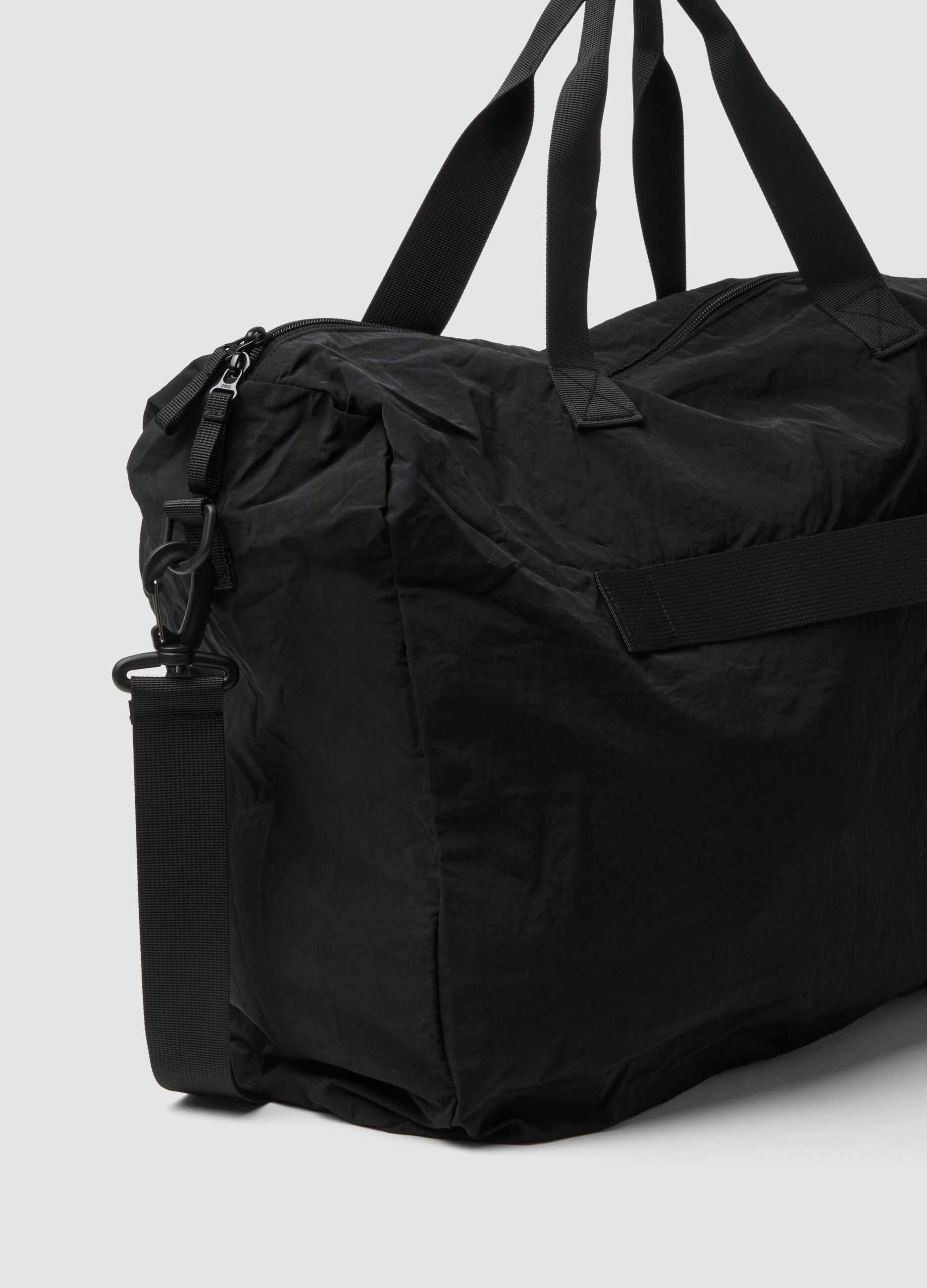 Black foldable travel bag with shoulder strap and zipped pockets