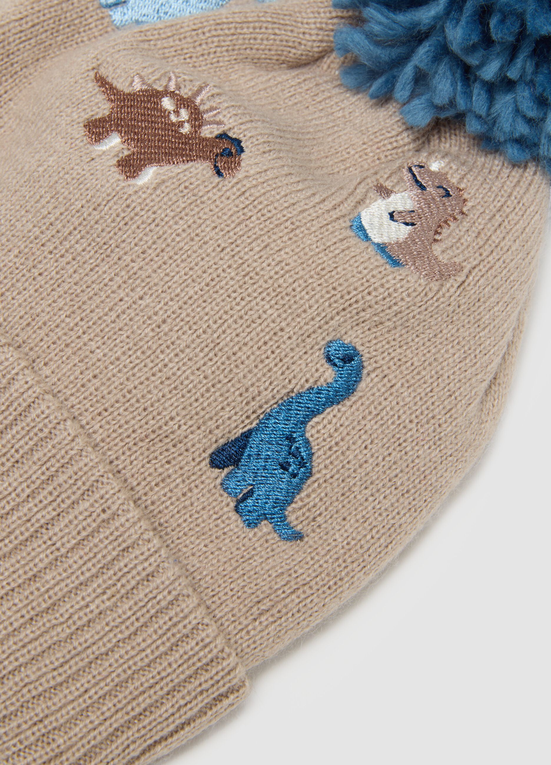 Beige hat with pom‑pom and dinosaurs