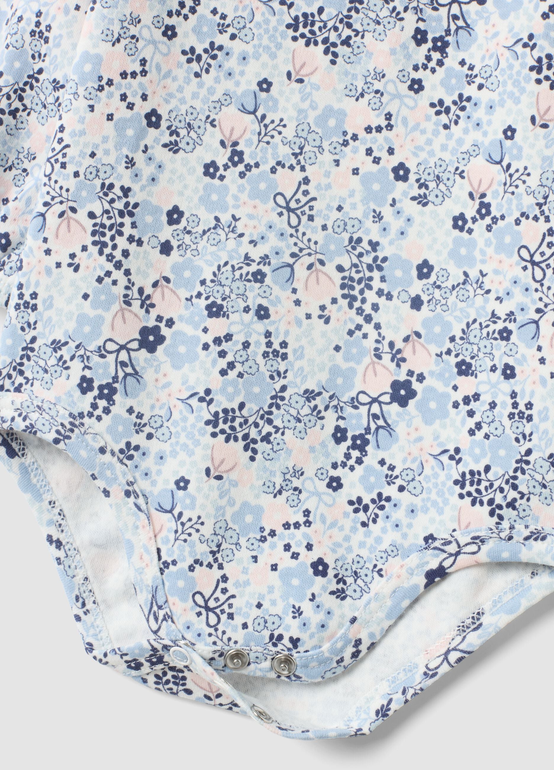 Body branco de algod&atilde;o org&acirc;nico para beb&eacute; menina com gola com folhos e estampado floral