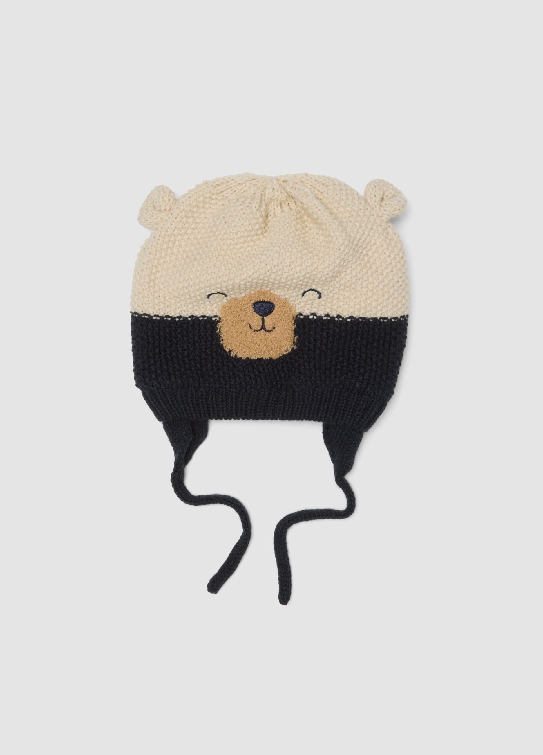 Blue knitted hat with teddy bear motif and ties