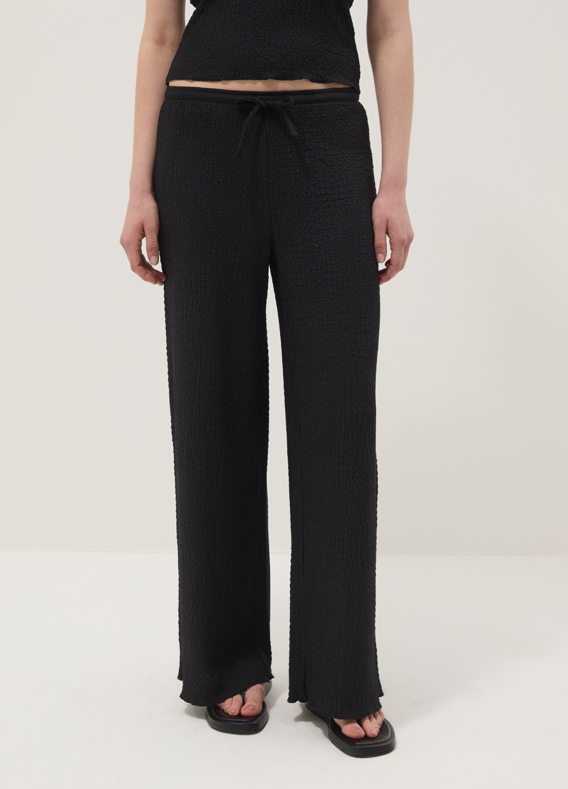 Black stretchy wide-leg trousers with crinkled texture