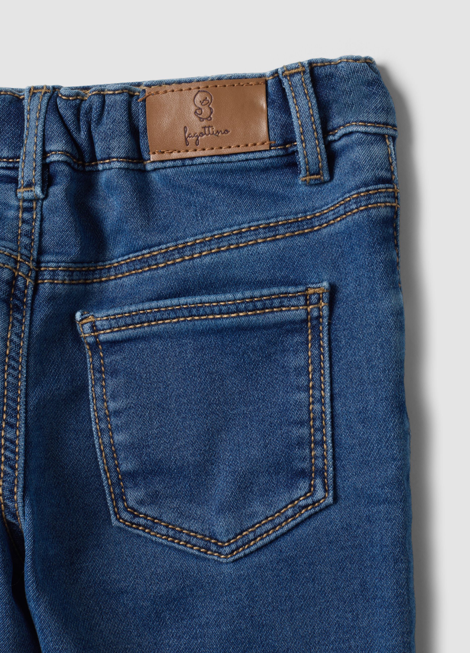 Blue stretch cotton jeans with varsity-style appliqu&eacute;s for baby boy