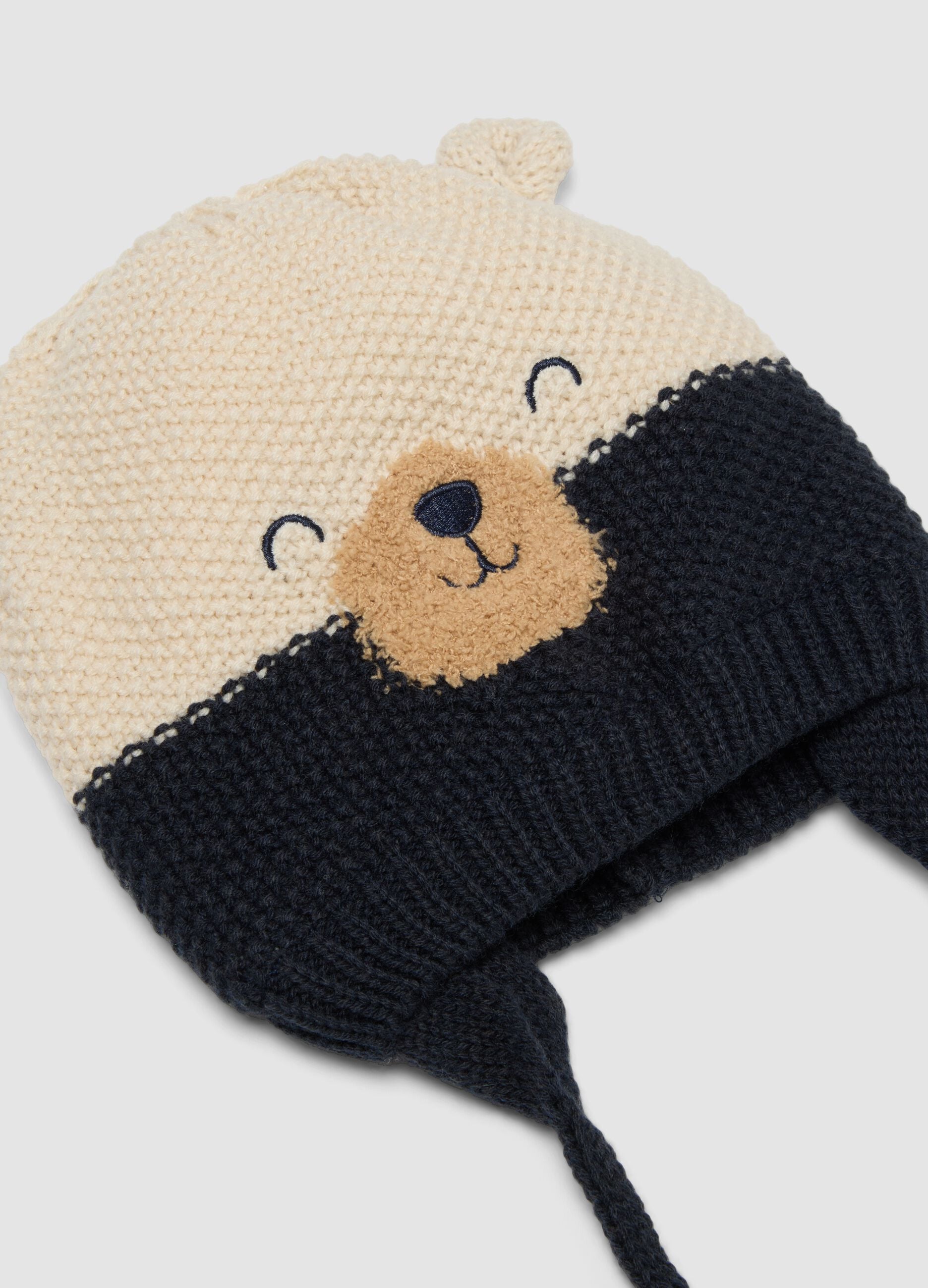 Blue knitted hat with teddy bear motif and ties