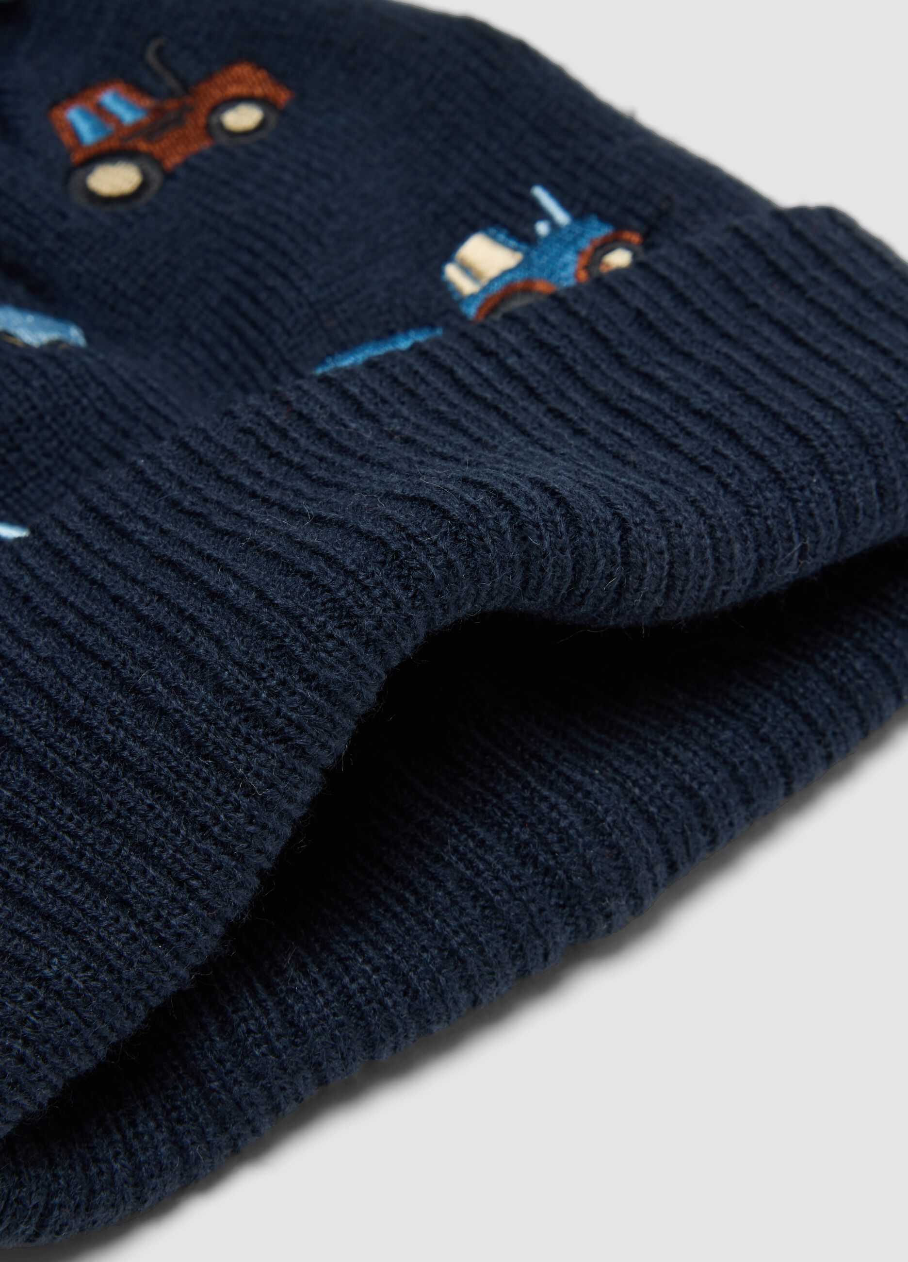 Blue knitted hat with pompom and tractor embroidery
