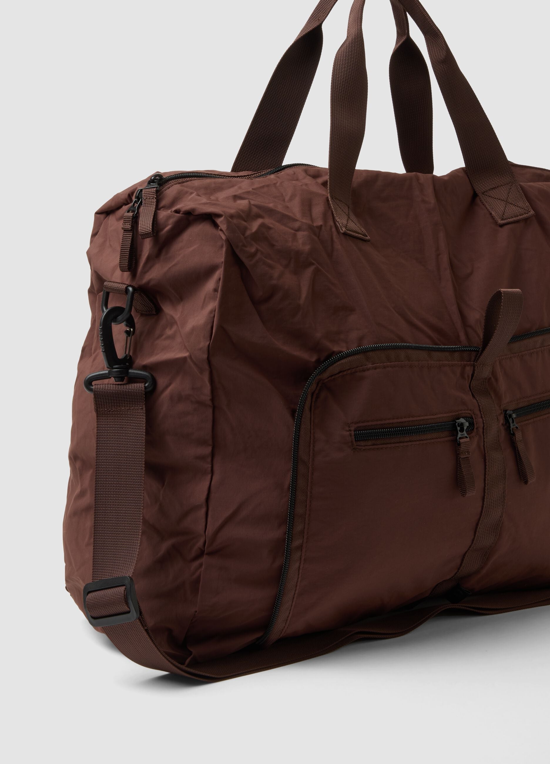Brown foldable travel bag with shoulder strap and zip pockets